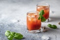 Tomato juice or Bloody Mary iced cocktail with bazil leaves in two glasses for drink menu on blue textured background Royalty Free Stock Photo