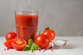 Tomato juice in a glass with falling salt , fresh tomatoes, basil and pepper