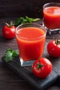 Tomato juice in glass glasses and fresh ripe tomatoes on a branch. Dark wooden background with copy space. Royalty Free Stock Photo