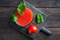 Tomato juice in glass glasses and fresh ripe tomatoes on a branch. Dark wooden background with copy space. Royalty Free Stock Photo