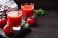 Tomato juice in glass glasses and fresh ripe tomatoes on a branch. Dark wooden background with copy space Royalty Free Stock Photo