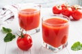 Tomato juice in glass glasses and fresh ripe tomatoes on a branch. White wooden background with copy space. Royalty Free Stock Photo