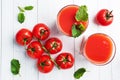 Tomato juice in glass glasses and fresh ripe tomatoes on a branch. White wooden background with copy space. Royalty Free Stock Photo