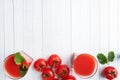 Tomato juice in glass glasses and fresh ripe tomatoes on a branch. White wooden background with copy space. Royalty Free Stock Photo