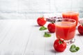 Tomato juice in glass glasses and fresh ripe tomatoes on a branch. White wooden background with copy space. Royalty Free Stock Photo