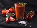 Tomato juice in a glass on a black background.