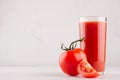 Tomato juice in glass with tomato and juicy slice on white wood table, copy space, closeup. Royalty Free Stock Photo