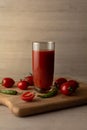 Tomato juice in a tall glass glass, cherry tomatoes, hot peppers on a cutting board, wooden background. Studio shot Royalty Free Stock Photo