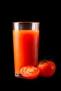 Tomato juice in a tall glass glass with natural fresh tomatoes on a black background Royalty Free Stock Photo