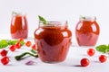 Tomato ketchup sauce with cherry tomatoes and red hot chili peppers, garlic and herbs in a glass jar on white background. Royalty Free Stock Photo