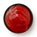 Tomato ketchup in small black ceramic dish isolated on white. Top view