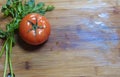 Tomato and leaves of parsley and fennel on a wooden board, flat lay