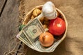 tomato onion garlic potatoes in a wicker basket with dollars on a wooden table, vegetables