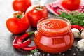 Tomato paste, puree in glass jar and fresh tomatos on dark background. Hot vegetable sauce with chili pepper ant tomatoes Royalty Free Stock Photo