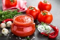 Tomato paste, puree in glass jar and fresh tomatos on dark background. Hot vegetable sauce with chili pepper ant tomatoes Royalty Free Stock Photo