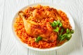 Tomato rice and chicken quarters on a white plate