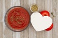 Tomato sauce in clear bowl with oregano spice and red vine ripe tomatoes on weathered wood background Royalty Free Stock Photo