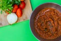 Tomato sauce .Composition on green background with bowl of fresh tomato sauce the ingredients, tomato, onion, basil are on the