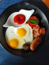 Tomato sauce dropped in lip-shape ceramic plate with two fried eggs and grilled sauce,bacon,mushroom and tomato