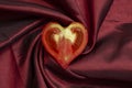 tomato slice shaped like a heart, on radial satin folds Royalty Free Stock Photo