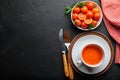 Tomato soup, fresh herbs, dinnerware on dark textured table Royalty Free Stock Photo