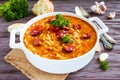 Tomato soup with orzo and smoked sausages in white casserole on wooden rustic table. Royalty Free Stock Photo