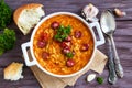 Tomato soup with orzo and smoked sausages in white casserole on wooden rustic table. Fresh bread and parsley, vintage spoon Royalty Free Stock Photo