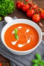 Tomato soup puree in a bowl with cream and fresh basil leaves on a dark wooden background. Copy space. Top view Royalty Free Stock Photo