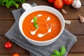 Tomato soup puree in a bowl with cream and fresh basil leaves on a dark wooden background. Copy space. Top view Royalty Free Stock Photo