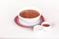 Tomato soup,  served with sour cream and extra tomato sauce,  white and red plate,  light background,  isolated Royalty Free Stock Photo