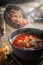 Tomato soup with vegetables and meat is poured into a bowl from the ladle from which steam comes, tasty, appetizing