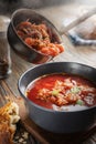 Tomato soup with vegetables and meat is poured into a bowl from the ladle from which steam comes, tasty, appetizing