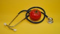 Tomato and stethoscope on yellow background