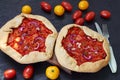 Tomato tarts with onion rings on the wooden board decorated with various cherry tomatoes. Traditional Italian vegetarian food