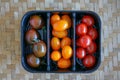 Tomato Varieties ,Type and color mixed together in black plastic basket on wooden floor Royalty Free Stock Photo