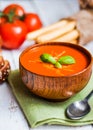 Tomatoe soup with bread sticks and basil on wooden background