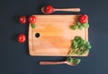 Tomatoes, arugula leaves and green basil leaves on wooden cutting board on dark background Royalty Free Stock Photo