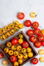 Tomatoes assortment on rustic table in wooden box red yellow whole and cut Royalty Free Stock Photo