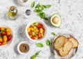 Tomatoes, avocado, basil, olive oil, bread - ingredients for bruschetta. On a light background Royalty Free Stock Photo