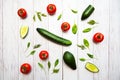 Tomatoes, avocado, cucumbers, whole and halves, spinach leaves and dill, flat lay on a white wooden surface. Healthy food concept. Royalty Free Stock Photo