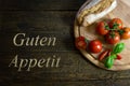 Tomatoes with bread on wooden table, text Guten Appetit