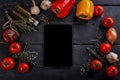 Tomatoes, bell peppers, garlic, olive oil and a cutting board on a black wooden table. Dark contrast background with vegetables Royalty Free Stock Photo