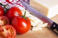 Tomatoes and cheese with knife on chopping board Royalty Free Stock Photo