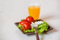 Tomatoes and cheese slices lie on a sheet of fresh salad in a plate. Royalty Free Stock Photo