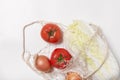 Tomatoes, chinese cabbage, onions in string bag on white background Royalty Free Stock Photo