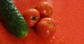 tomatoes and cucumber on a red background water droplets on the Royalty Free Stock Photo