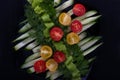 Tomatoes, cucumbers, parsley and dill in a black plate