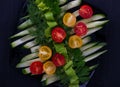 Tomatoes, cucumbers, parsley and dill in a black plate