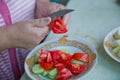 Women make salad .Dieting, healthy food, weight losing, well-being. Overweight fat woman slicing a tomato for salad. Tomatoes cut Royalty Free Stock Photo