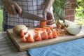 Tomatoes on cutting board with woman cutting carrot at the background